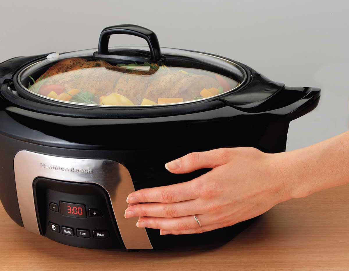 a hand touching the outside of a slow cooker