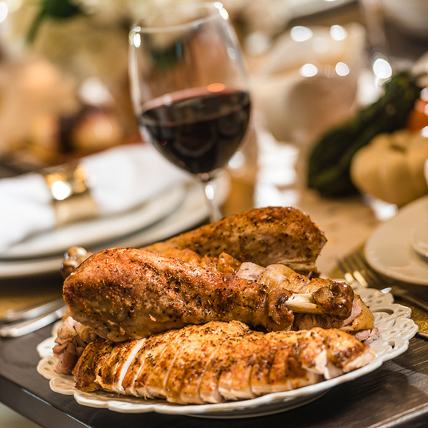 carved turkey on a plate with a glass of red wine