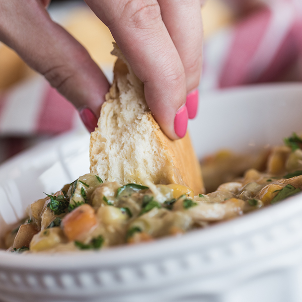 slow cooker chicken pot pie stew with a biscuit being dipped into it